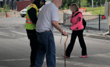 Construction worker helping elderly man cross road