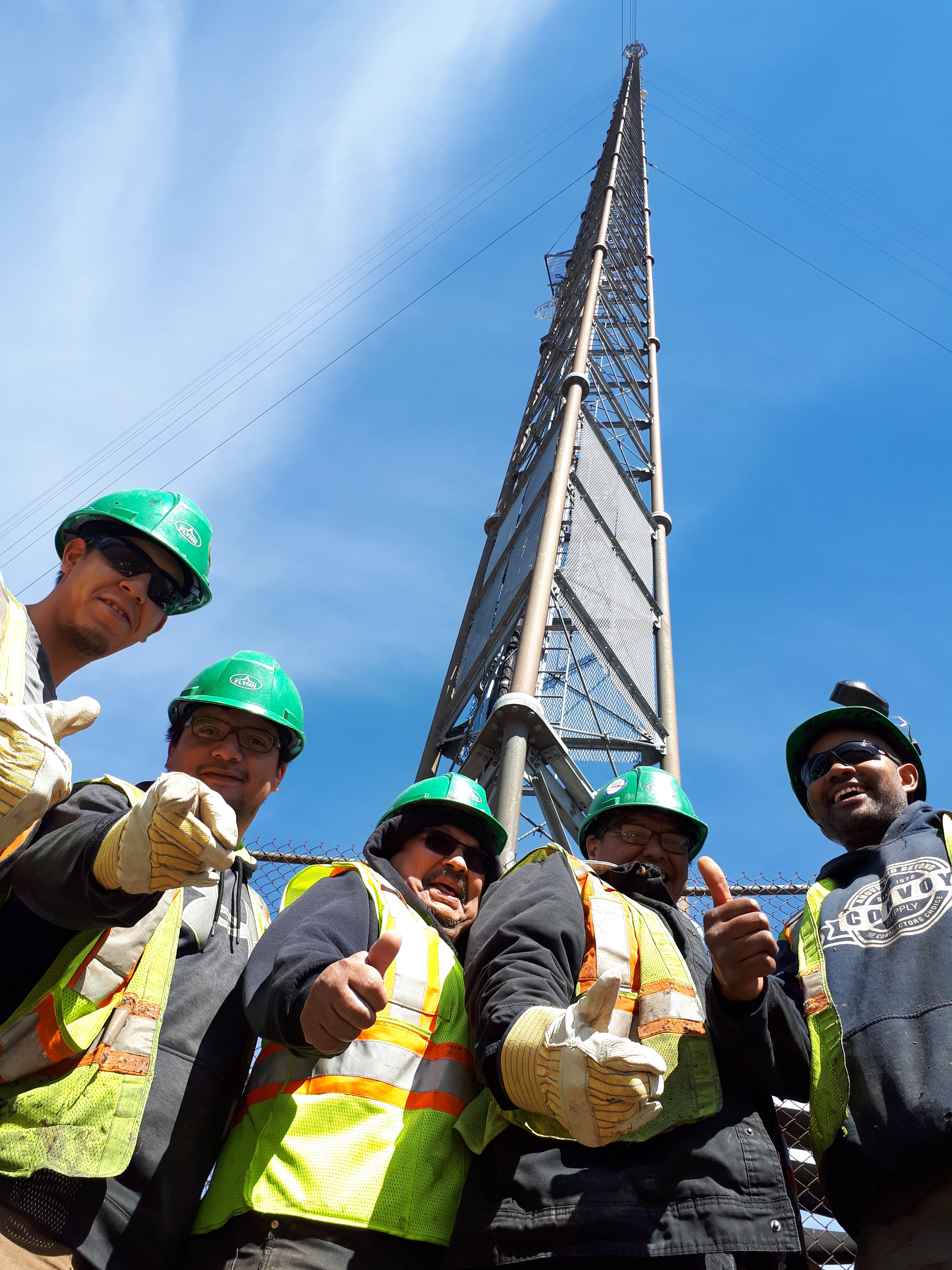 Five construction workers in front of radio tower